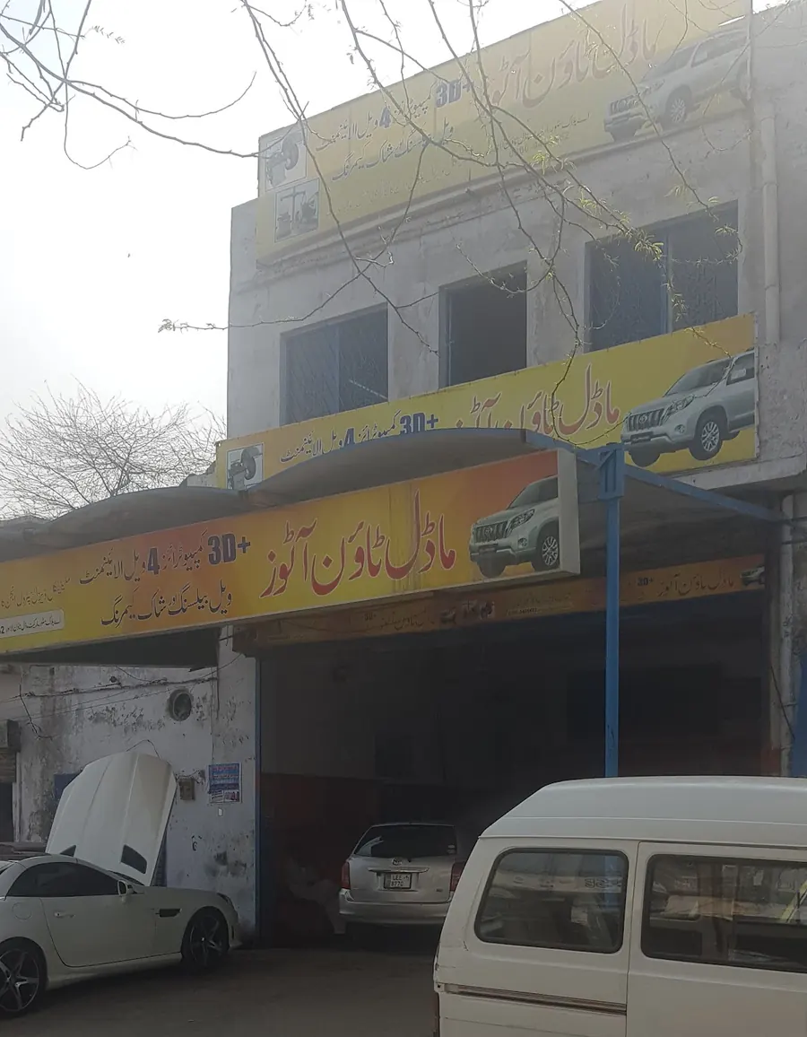 The Model Town Autos building from the lane, with three yellow boards
